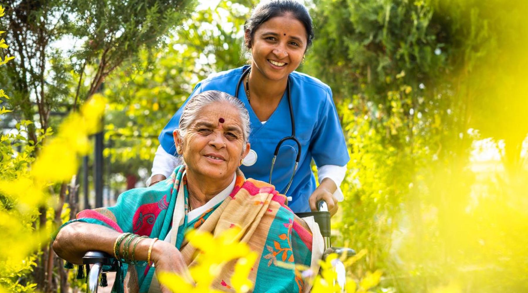 happy smiling Nurse taking senior woman on walk while on wheelchair